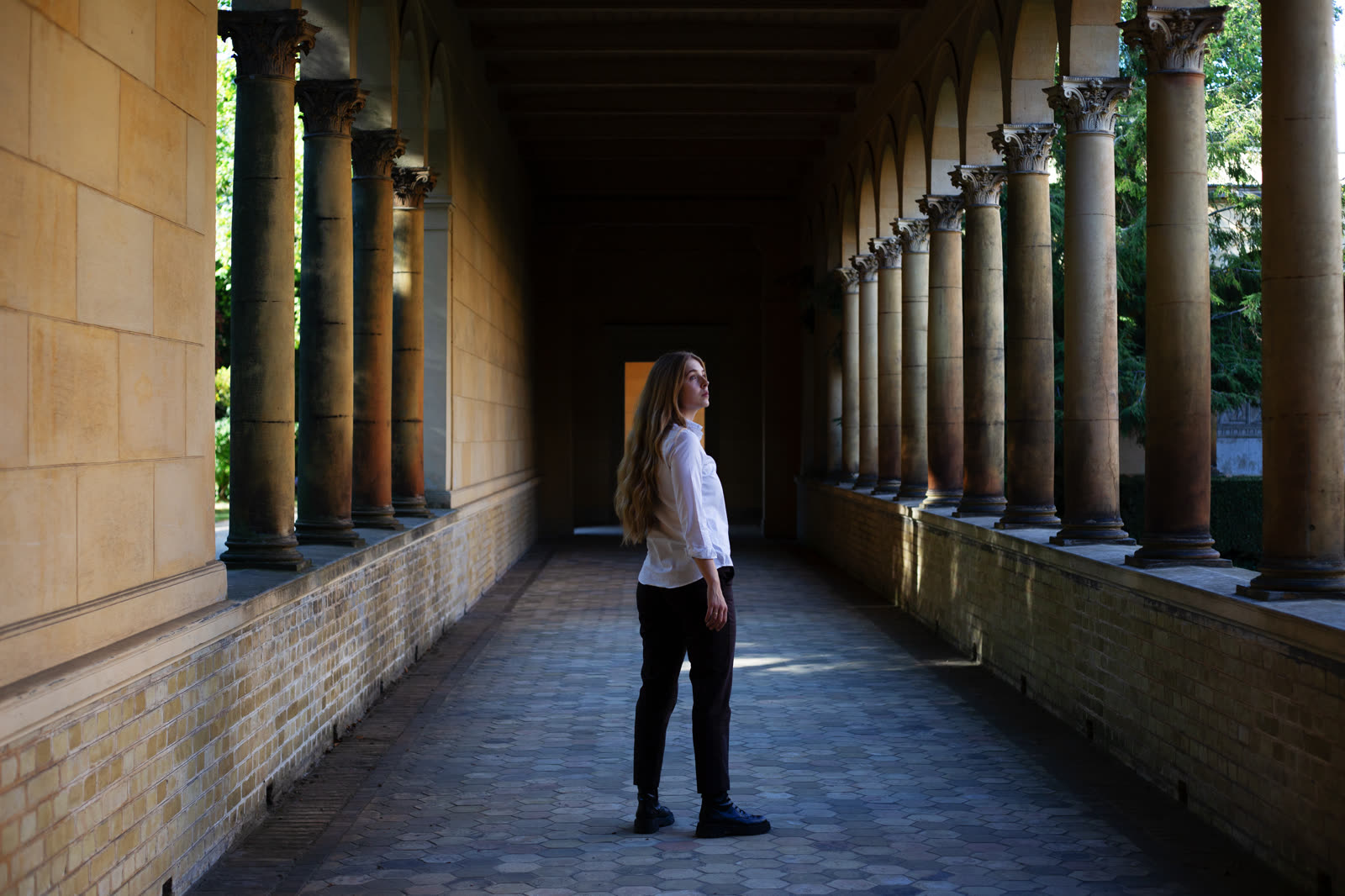 Person in a white shirt in a colonnade